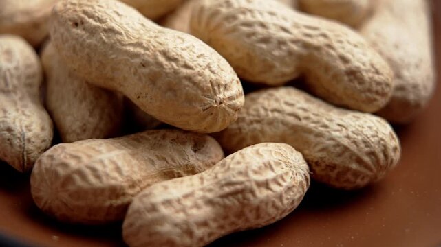 Close up of peanuts in shell. Roasted agricultural product in brown bowl. Macro. Rotation