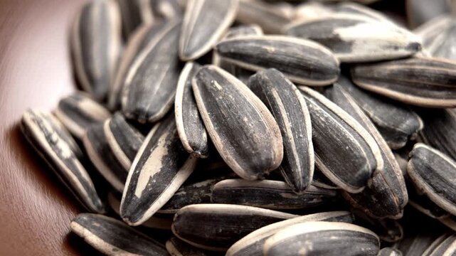 Unshelled whole roasted salted sunflower seeds in a brown bowl. Macro shot