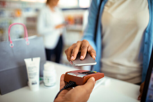 Woman paying with smartphone at pharmacy checkout
