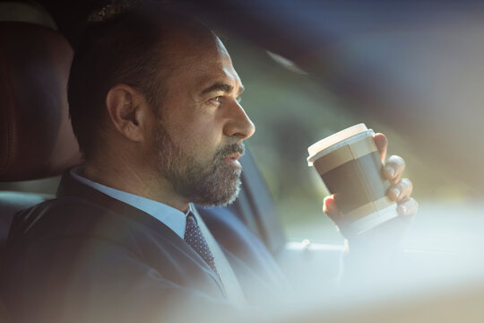 Businessman driving car with takeaway coffee cup