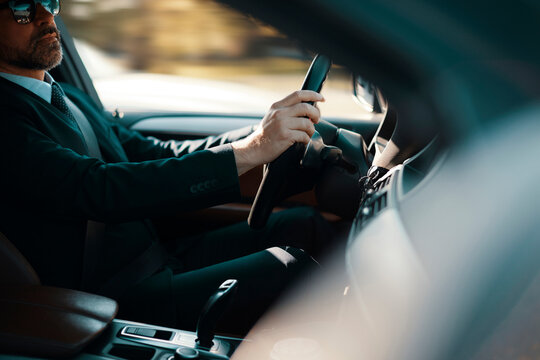 Professional man driving car in modern vehicle interior