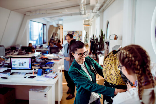 Fashion designers collaborating on dress in modern studio