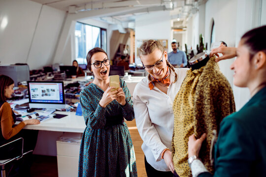 Fashion designers reviewing garment sample in modern office