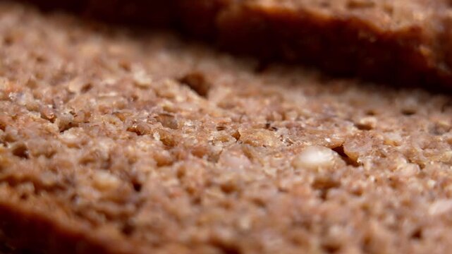 Whole grain rye bread slices with dense porous surface. High fiber nutrition and healthy diet ingredient. Rustic baked product. Macro shot. Rotation