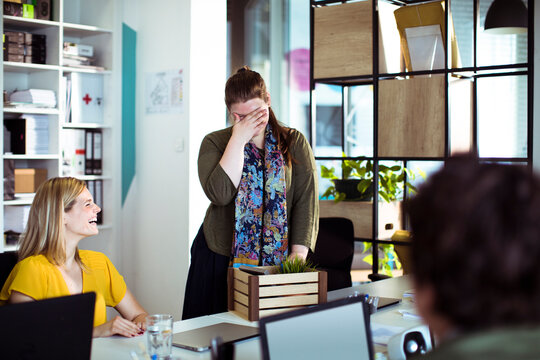 Coworkers surprising colleague with gift in modern office
