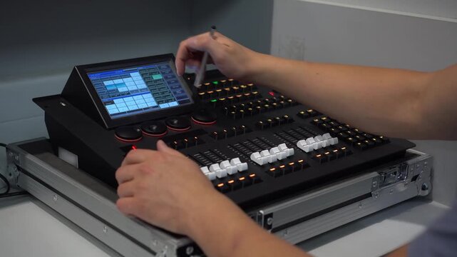 Man adjusting lighting mixer pressing buttons and using stylus on touch screen 4k