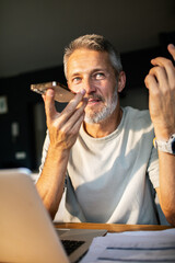 Middle-aged man using voice assistant at home office