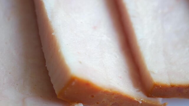 Delicious slices of salted or smoked pork fat, known as salo or lard, presented in an extreme macro view, revealing the delicate texture and savory details of this traditional cured meat product