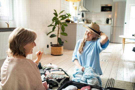 Two senior women packing suitcases at home for vacation