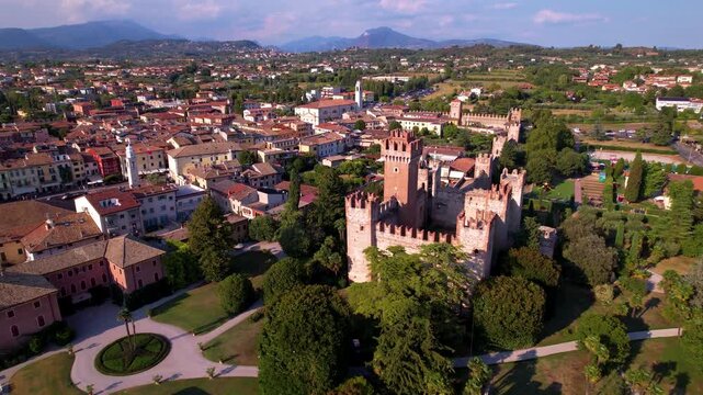Italy Lake Garda aerial drone fly-in to Scaliger castle and reveal of Lazise old town and lake scenery. Medieval fortress and harbor with boats 4k travel destination Veneto region landscape