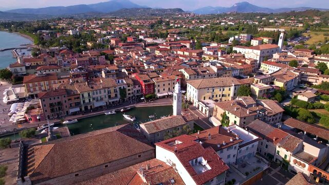 Italy Lake Garda aerial cinematic drone flight along Lazise promenade, Scenic waterfront with boats and colorful old town near Verona. Luxury travel destination Lago di Garda scenery 4k landscape