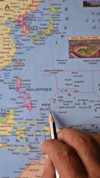Male Hand Pointing Palau on Map with Pencil &ndash; Top View, Vertical Footage