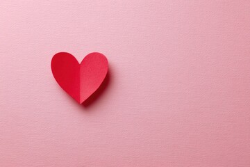 Obraz premium Red paper heart on pink textured background symbolizing love, romance, affection, and Valentine's Day concept with minimalistic style and copy space for text or design.