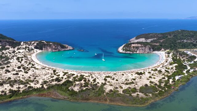 Establishing aerial view of the half circle shaped Voidokilia beach in Messinia, Peloponnese, Greece, with sand dunes and turquoise sea