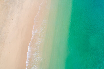 Fototapeta premium Bird eye perspective of calm sea rolling onto clean golden sand The Concept of Relaxation