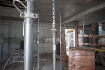 Inside a structure under active development, numerous gleaming metal adjustable props firmly...