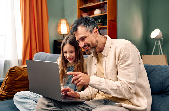 Father and daughter using laptop at home.