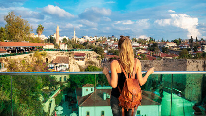 Fototapeta premium Young female traveler with a backpack enjoying the panoramic view of Kaleiçi old town in Antalya, Turkey.