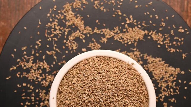 Top View of Carom Seeds (Ajwain) in White Bowl on Black Background &ndash; Rotating Footage
