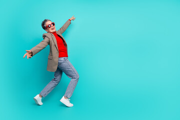 Joyful senior businesswoman dancing blue teal background wear red shirt checkered jacket lifestyle...