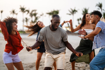 A diverse group of multicultural friends enjoying summer moments on the beach, dancing, laughing © NDABCREATIVITY