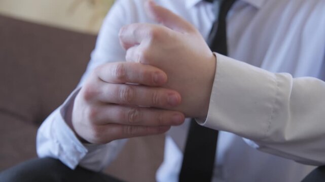 A man in a business white and black suit with a tie stretches and cracks his knuckles