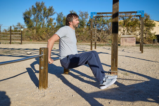Man performing tricep dips on metal bars during outdoor workout