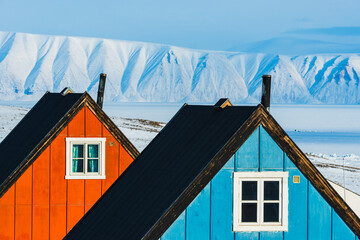 Colorful buildings in Qaanaaq, Greenland with snowy mountains in the background during bright daylight © Mikael