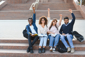 Fototapeta premium Diverse students celebrating academic success on campus stairs