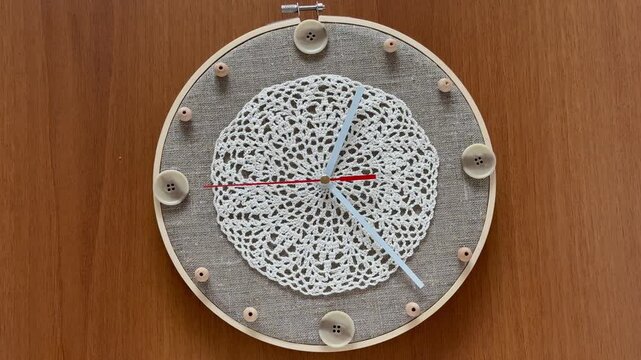 Time for crafts and crochet. Video of handmade wall clock with buttons and beads instead of numbers and lace doily to decorate the dial on wooden background. Hobbies and relaxation through needlework