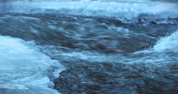 Scenes of flowing water along an outdoor riverbank in winter
