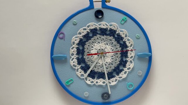 Time for craft, knit and crocheting. Video of handmade wall clock with knitting and sewing accessories instead of numbers and lace doily decorate dial in blue hoop. Concept of hobbies, leisure, needle