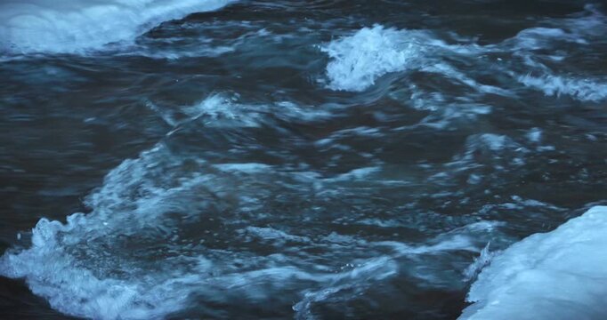 Scenes of flowing water along an outdoor riverbank in winter