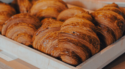 Freshly baked croissants arranged in a wooden tray on display