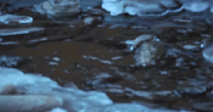 Scenes of flowing water along an outdoor riverbank in winter