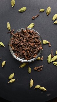 Top View of Cloves (Laung) in White Bowl Cardamom (Elechi) on Black Background &ndash; Rotating Footage