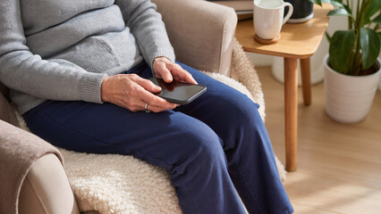 Fototapeta premium An elderly woman holds a smartphone, Her hands gently grip the device, The senior woman uses mobile technology, A grandmother interacts with an app, She navigates the touch screen carefully