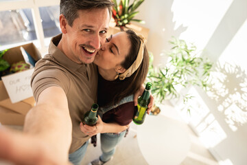 Fototapeta premium Couple enjoys time together while holding drinks in a bright indoor space during a home celebration