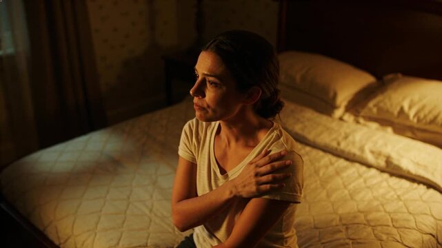 Vertical video: Woman feeling sore neck massaging shoulder on bed, wellness overlaying neck