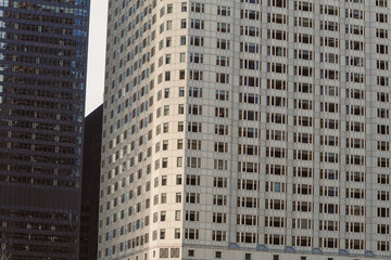 Fototapeta premium Modern buildings stand in a city during late afternoon with sunlight brightening the windows and creating shadows