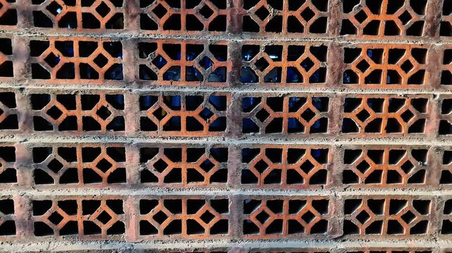 Cinematic close up footage of a uniquely patterned brick wall featuring decorative ventilation blocks arranged in a geometric layout.