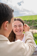 Obraz premium Boy putting daisy flower on sister's ear outdoors