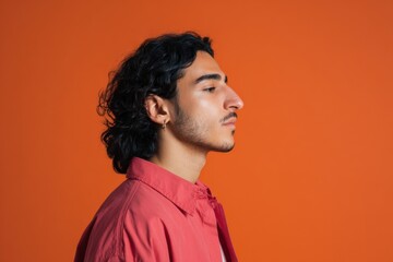 Obraz premium Male caucasian young profile orange background red shirt side view earring contemplative