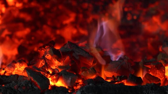 Burning charcoal surface with bright embers and dark texture creating a powerful abstract fire background.