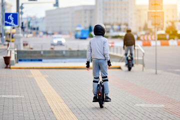 Men riding electric unicycle together through city street wearing safety gear and moving toward underground crossing in modern urban setting. Riders on self balancing unicycle driving on sidewalk © Tricky Shark