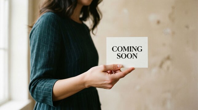 Anticipation revealed by a hand holding a coming soon announcement card