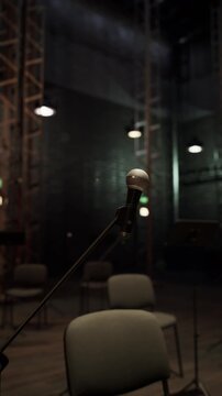A microphone stands ready on a dimly lit opera stage, surrounded by elegant decor. Chairs are set up, hinting at an upcoming performance, creating an atmosphere of anticipation.
