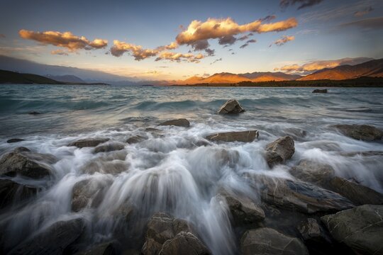 Stones on shore, lake with sunset swell, long time exposure, Lake Tekapo, Canterbury, South Island, New Zealand