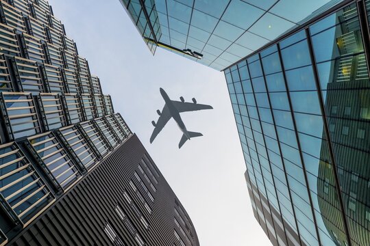 Airplane flying over skyscraper, low-angle view, London, England, United Kingdom
