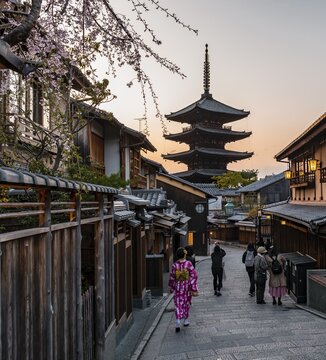 Pedestrian with kimono, Yasaka dori historical street in the Old Town with traditional Japanese houses, behind five-storey Yasaka pagoda of the Buddhist Hōkanji Temple, evening mood, Kyoto, Japan